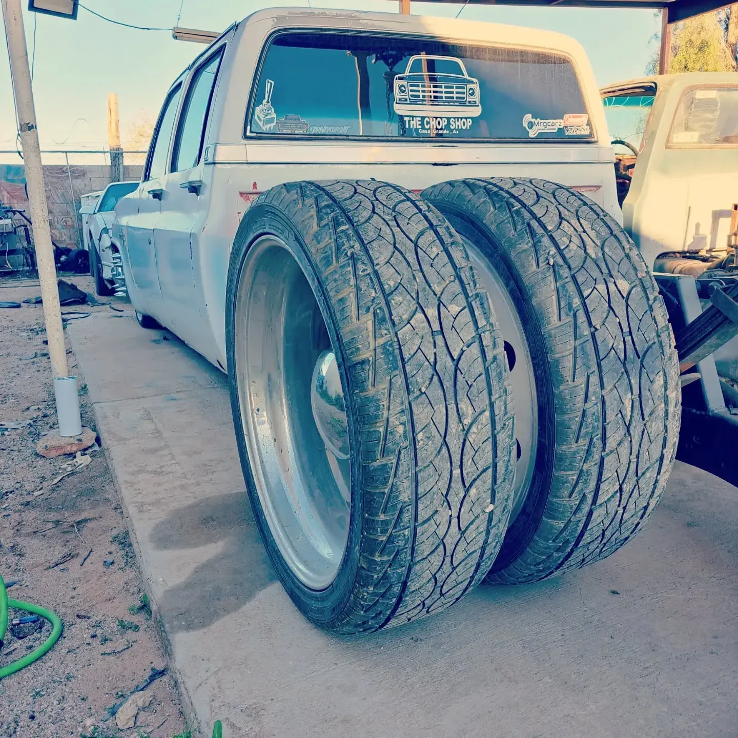 White pickup truck with dually tires on a concrete surface, possibly in a garage 