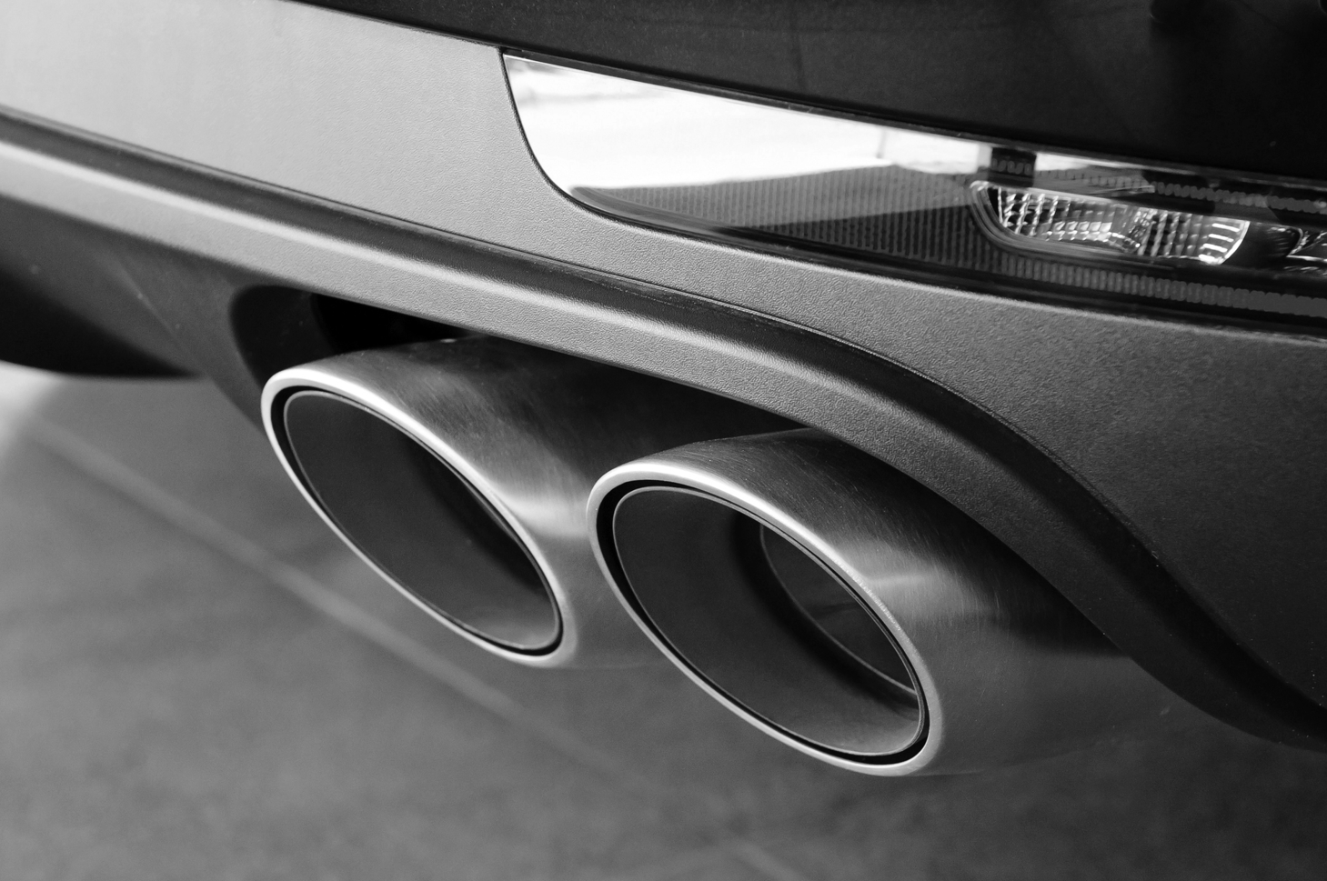 Primer plano de los tubos de escape dobles de un automóvil, realizados en cromo, en blanco y negro.