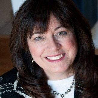 A man is sitting on a couch talking to two older people.