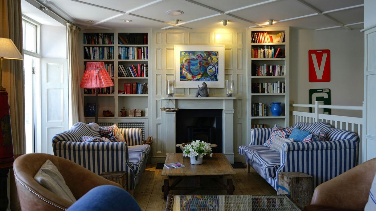 A cozy living room with striped blue and white sofas, built-in bookshelves, a fireplace, and two armchairs.