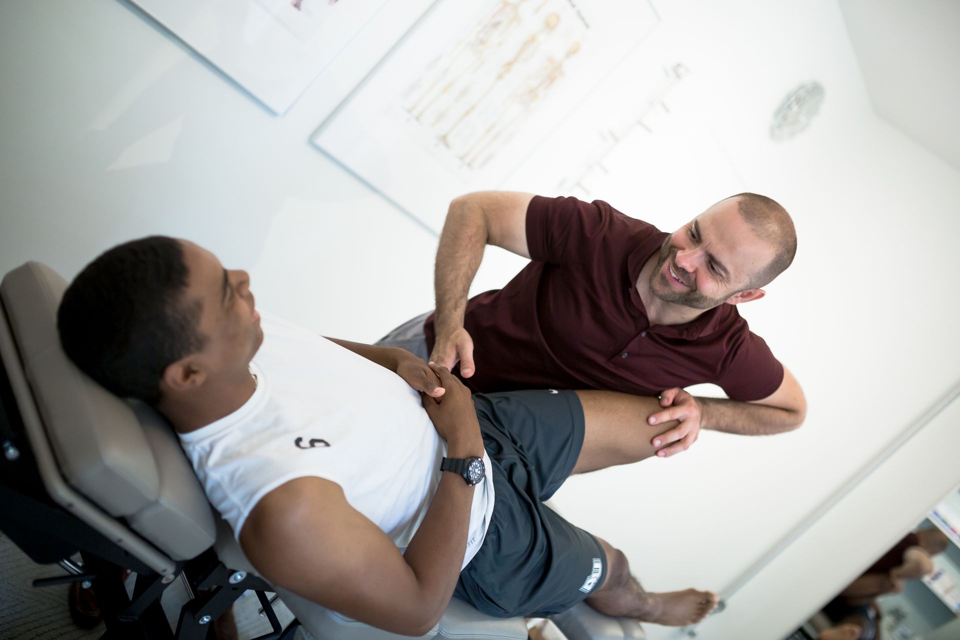 A man is laying on a table while another man stretches his leg.