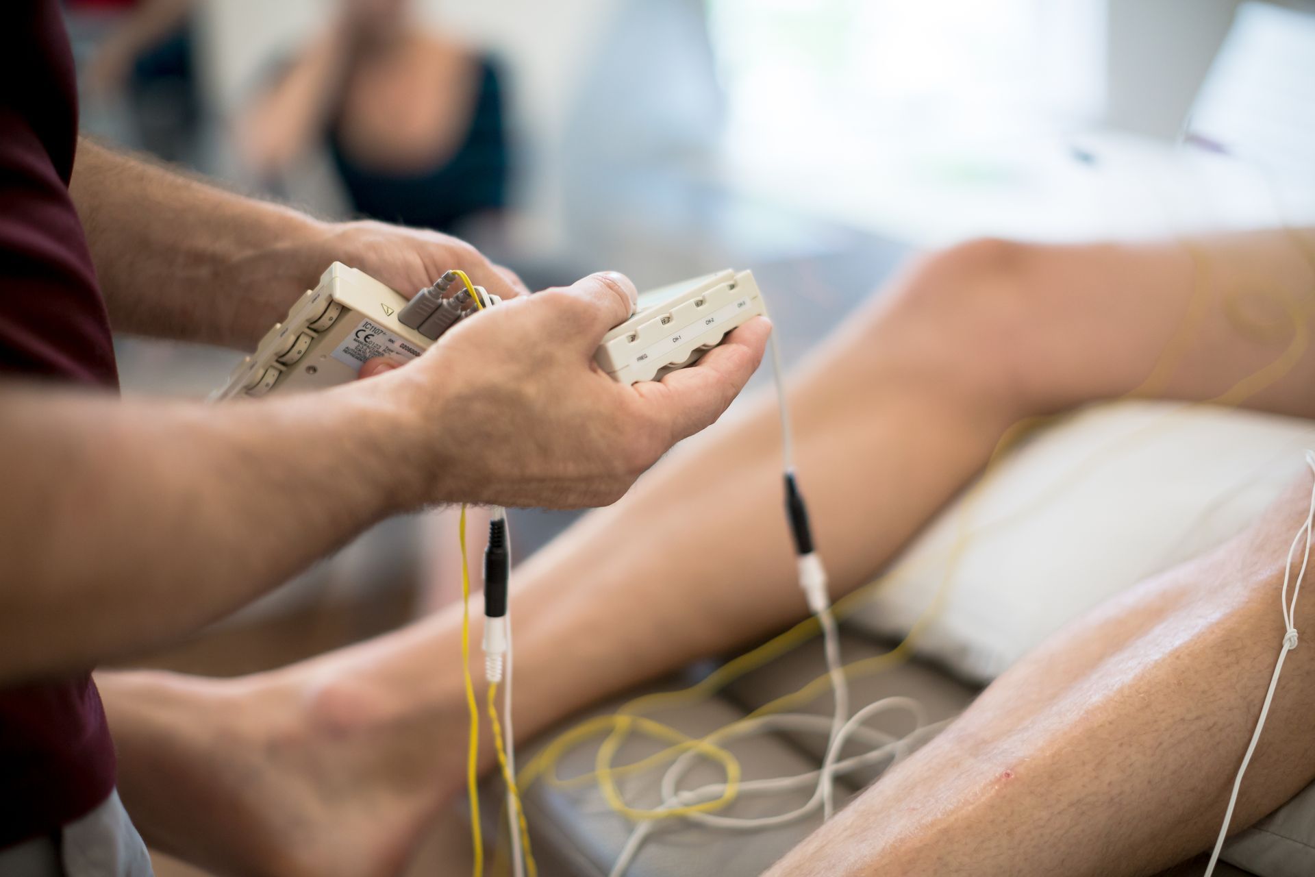 Person receiving acupuncture treatment with electrical stimulation on leg.
