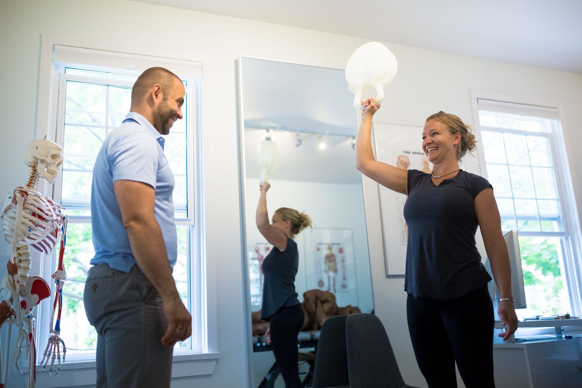 A man and a woman are playing with a light bulb in front of a mirror.