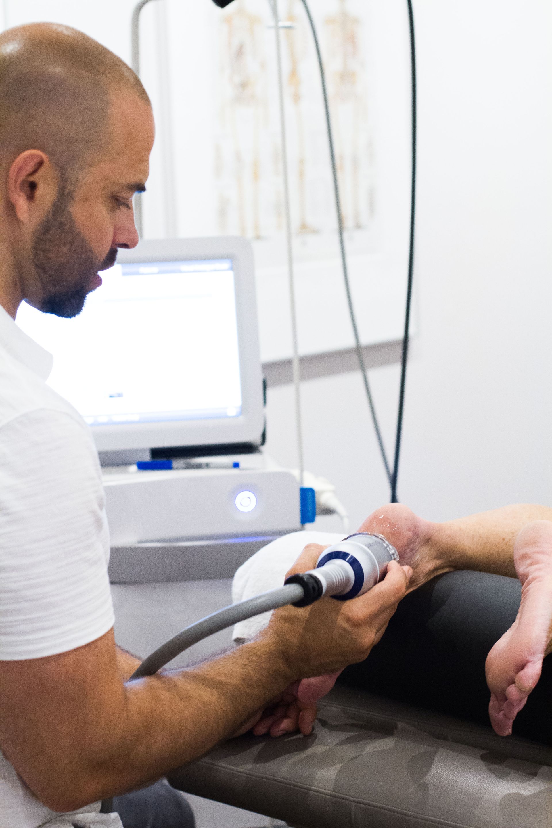 A man is using a machine to treat a patient 's foot.