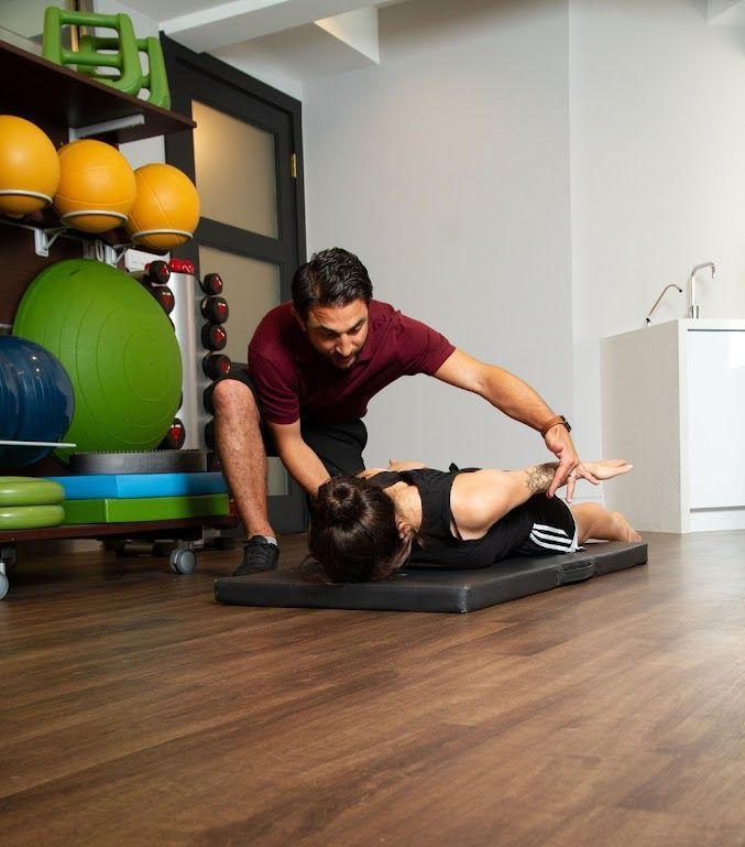 A man is helping a woman stretch on a mat