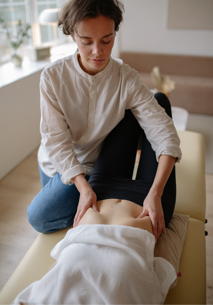 A man is helping a woman do exercises on a mat in a gym.