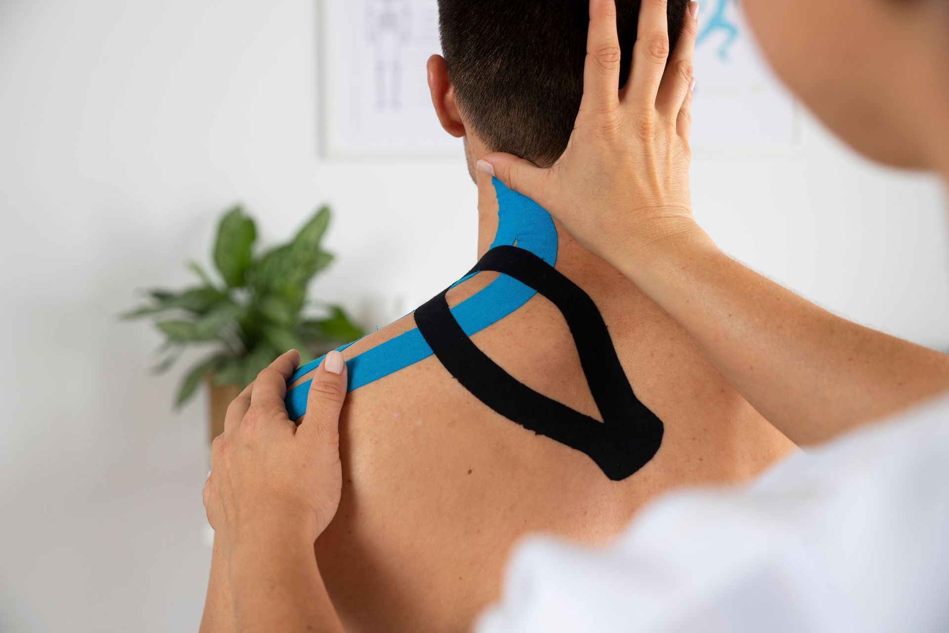 A person is putting kinesio tape on a man 's back.