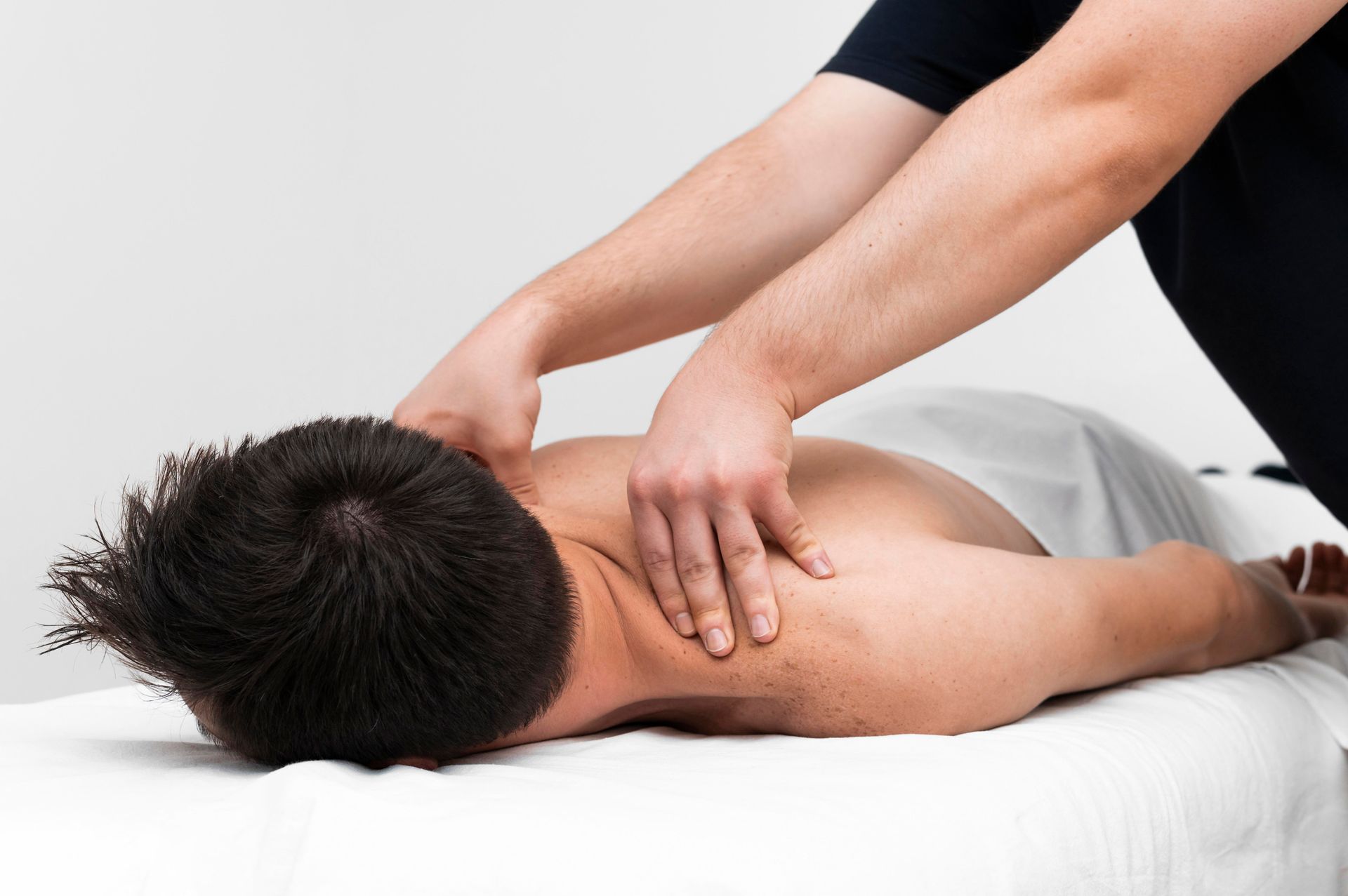 A man is laying on a bed getting a massage.