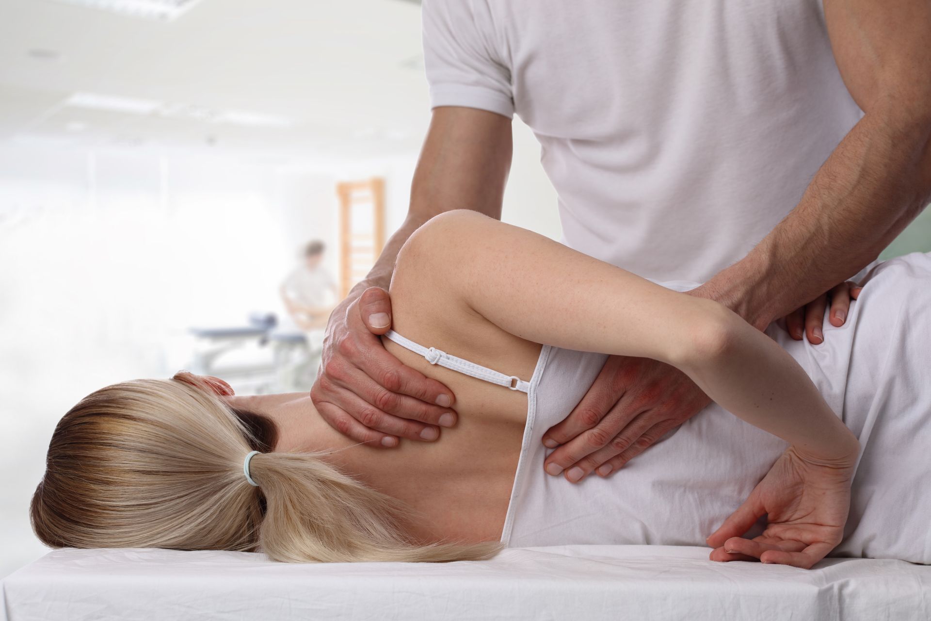 A woman is laying on a table getting a massage from a man.