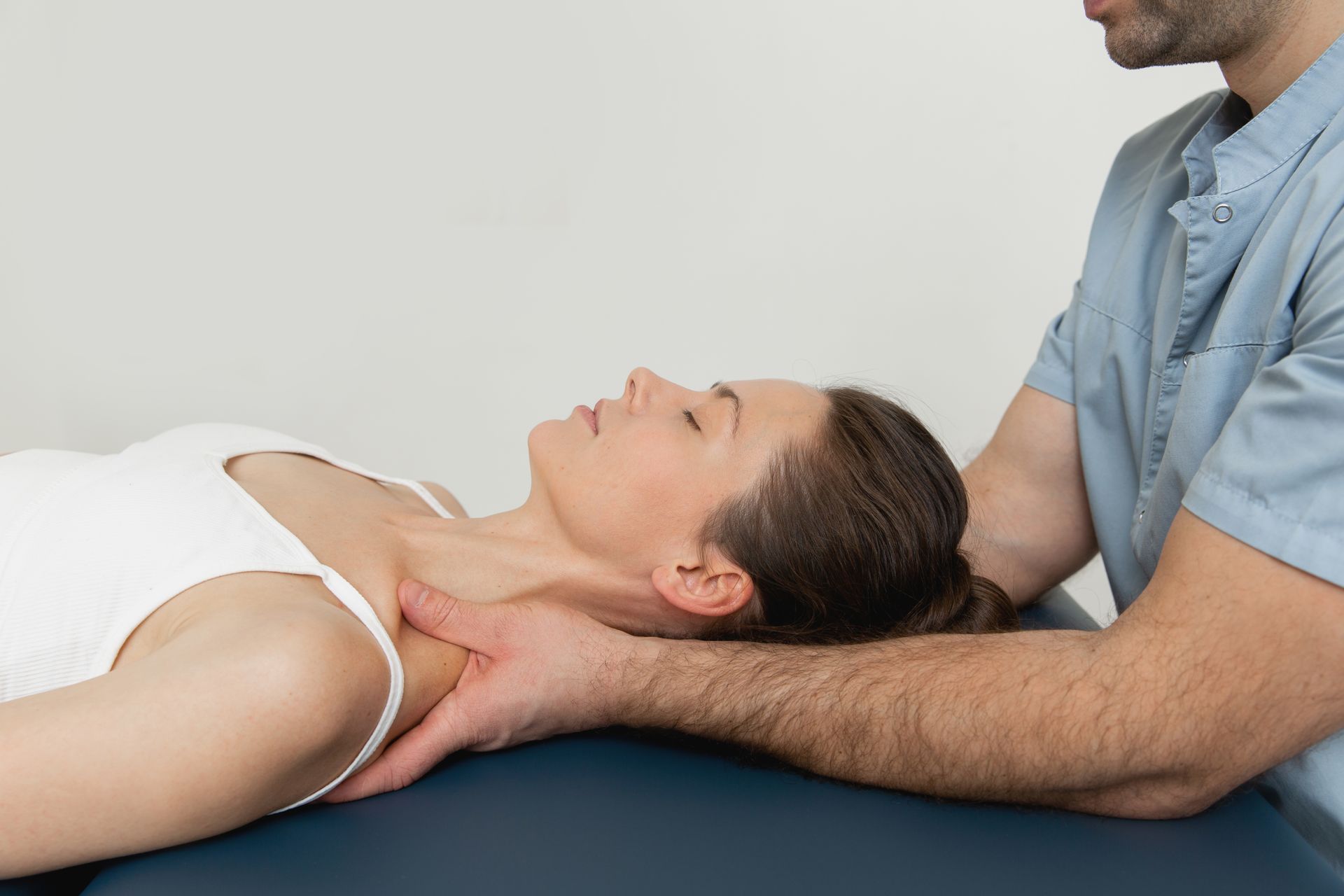 A man is giving a woman a neck massage on a table.