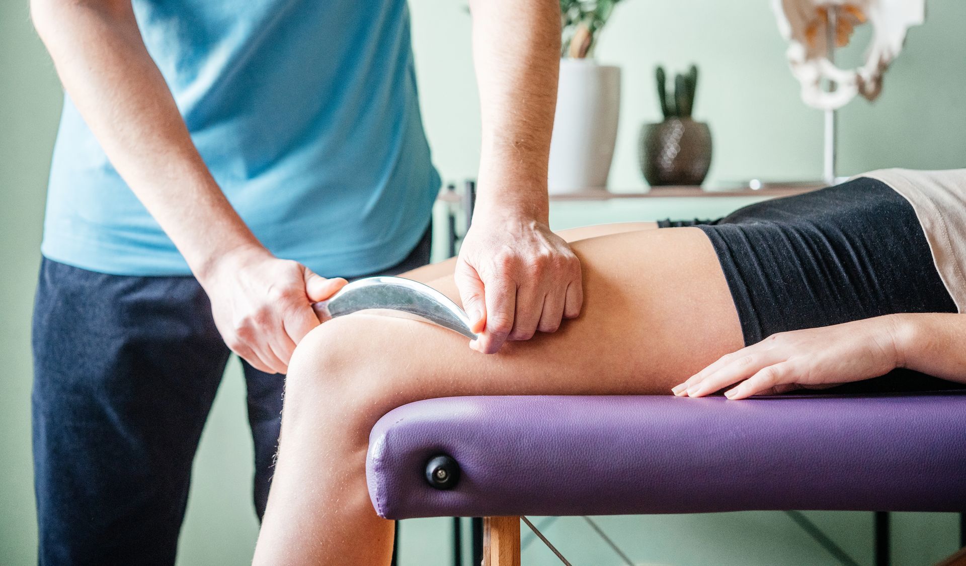 A woman is laying on a purple table getting a massage from a man.