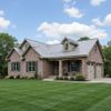 Brick house with gray roof, porch, and two-car garage. Lush green lawn and blue sky with clouds.