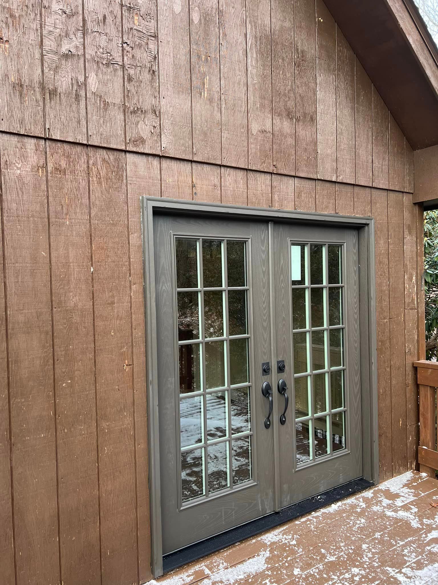Brown wooden building with double doors; reflecting outside.