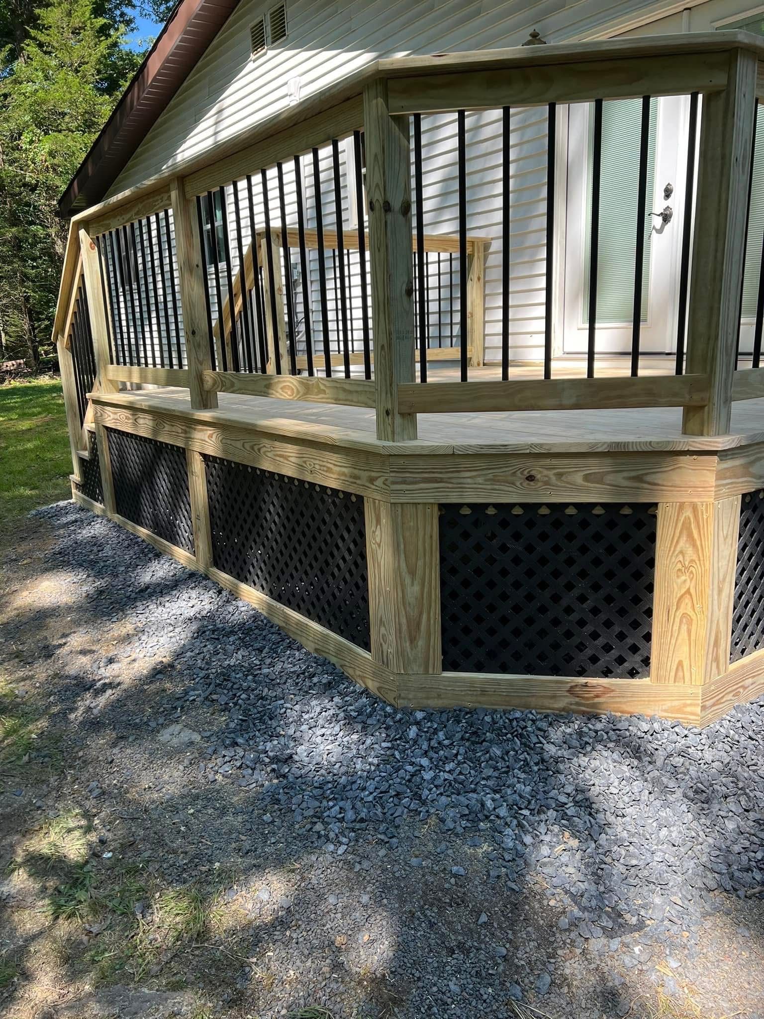 Wooden deck with black lattice skirting and black spindles, gravel ground.