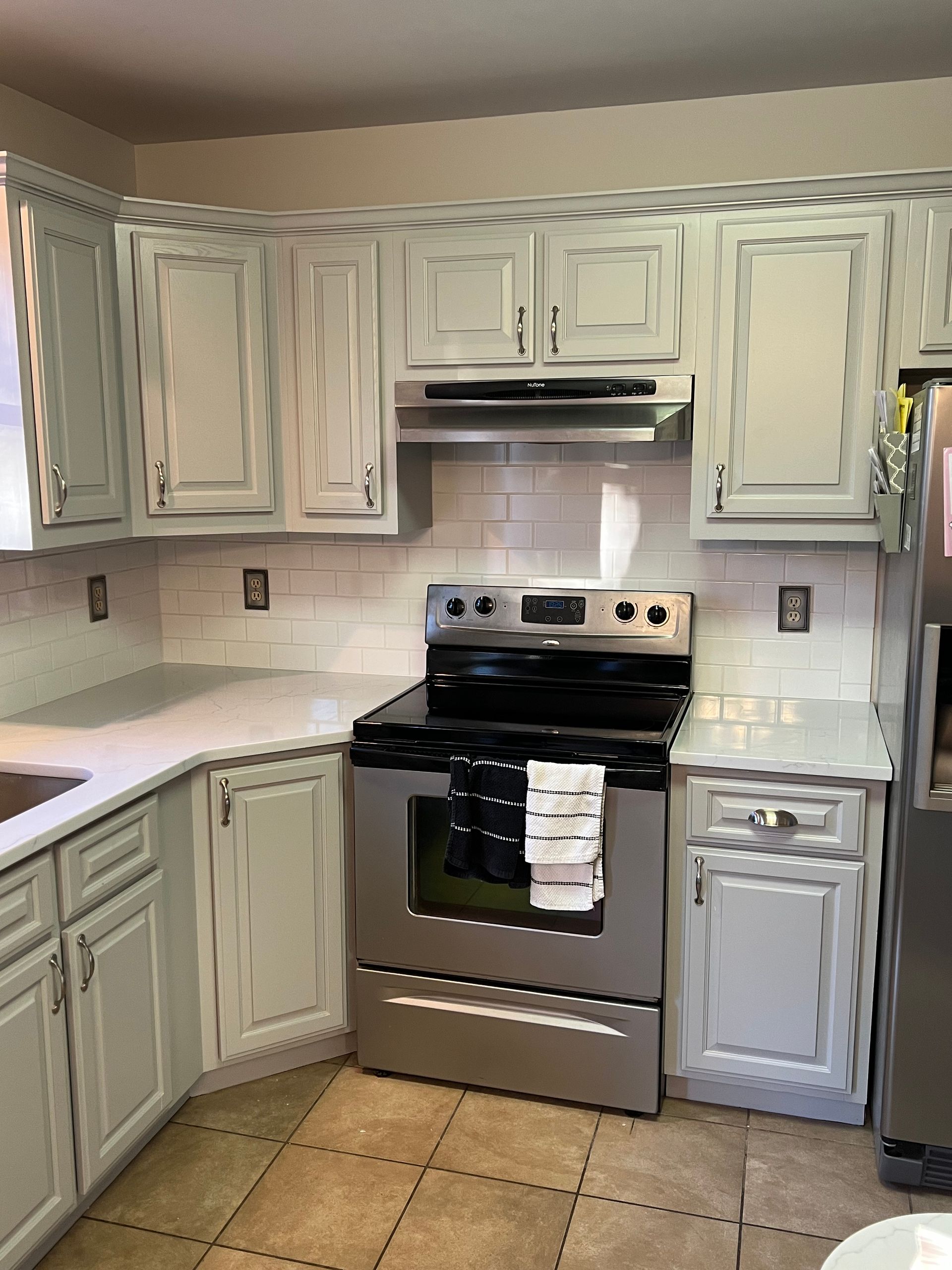 Kitchen with light blue cabinets, white countertops, stainless steel appliances, and a tile backsplash.
