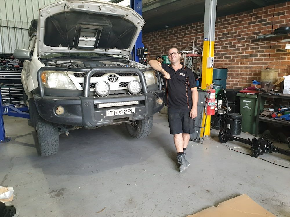 A Man Is Standing In Front Of 4x4 Repairing In A Garage  β 100% Automotive In South Nowra, NSW