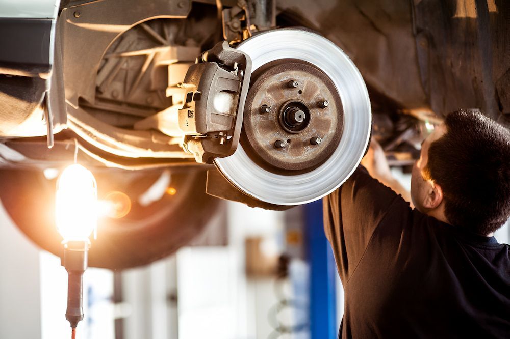A Man Is Working On The Brake System Of A Car β 100% Automotive In South Nowra, NSW