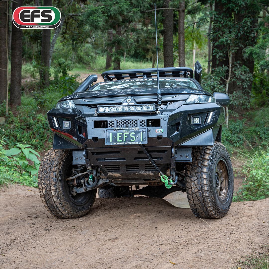 Modified black off-road truck on a dirt road in a wooded area; EFS logo in the top left. — 100% Automotive In South Nowra, NSW