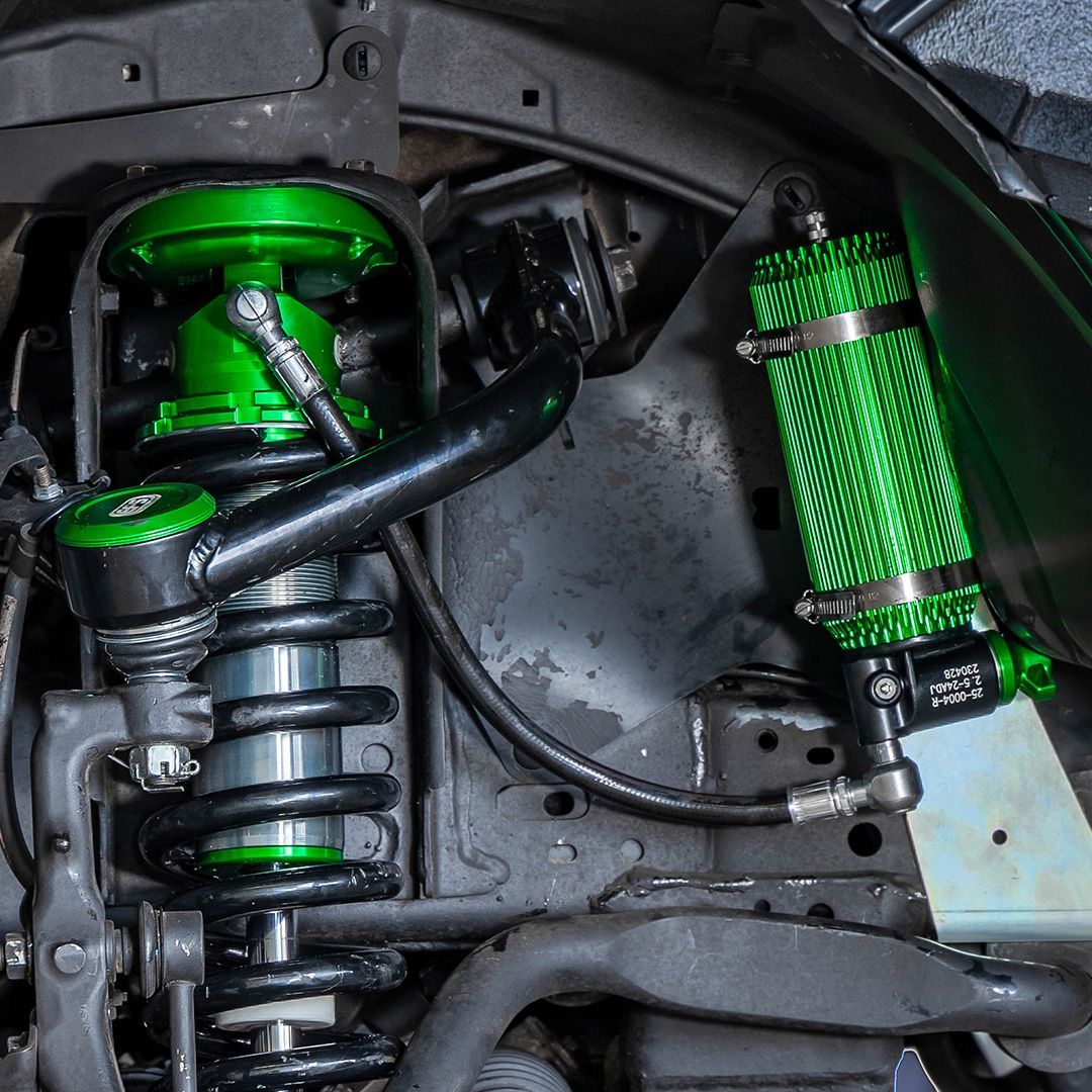 Green aftermarket suspension components on a vehicle's undercarriage. β 100% Automotive In South Nowra, NSW
