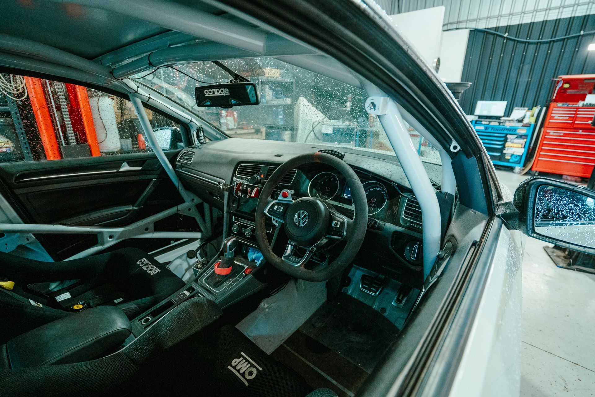 Interior view of a race car with roll cage, racing seats, steering wheel, and dashboard. β 100% Automotive In South Nowra, NSW