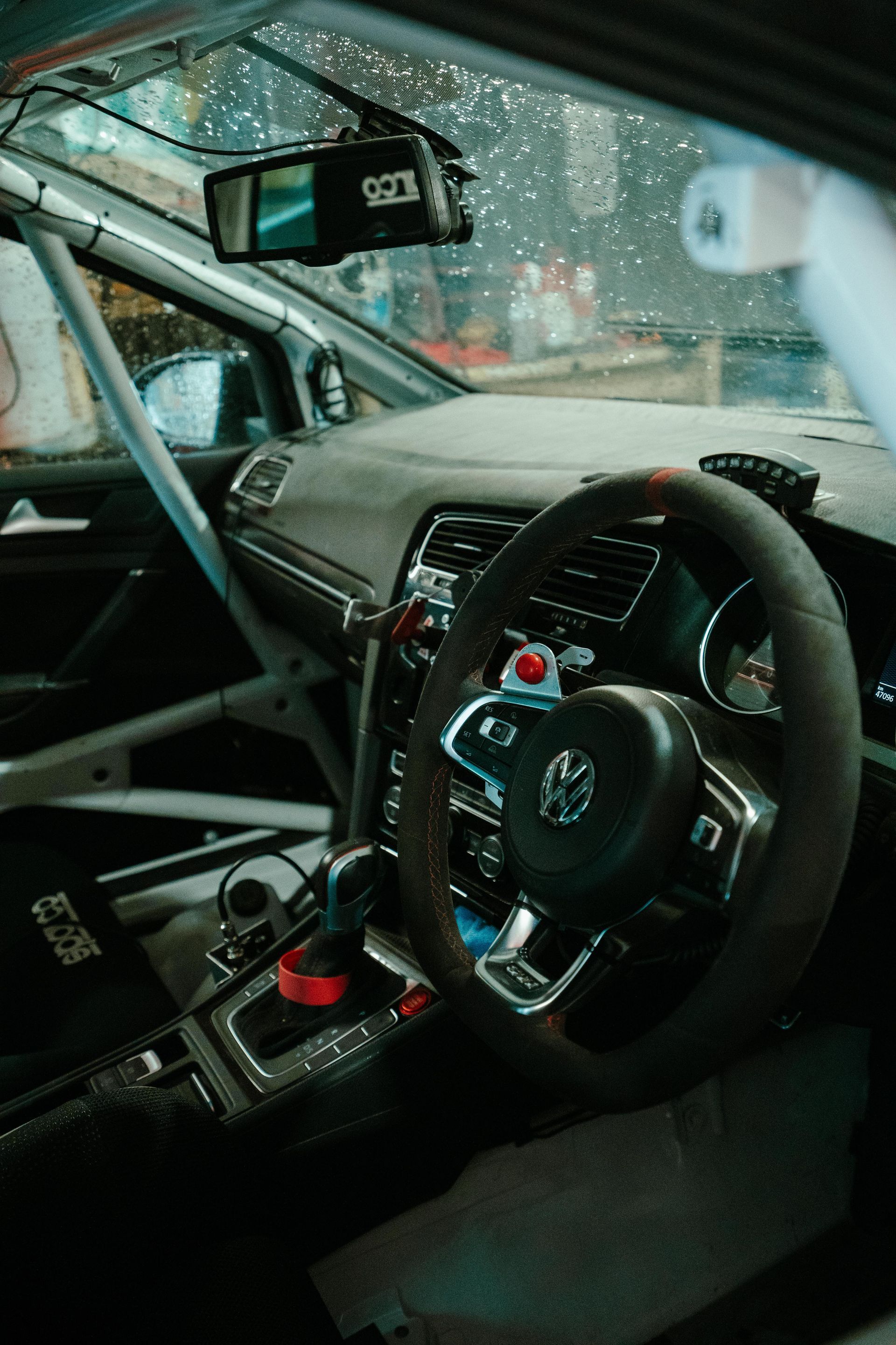 Interior of a race car, focusing on the steering wheel, dashboard, and roll cage. Dark, with minimal light. — 100% Automotive In South Nowra, NSW
