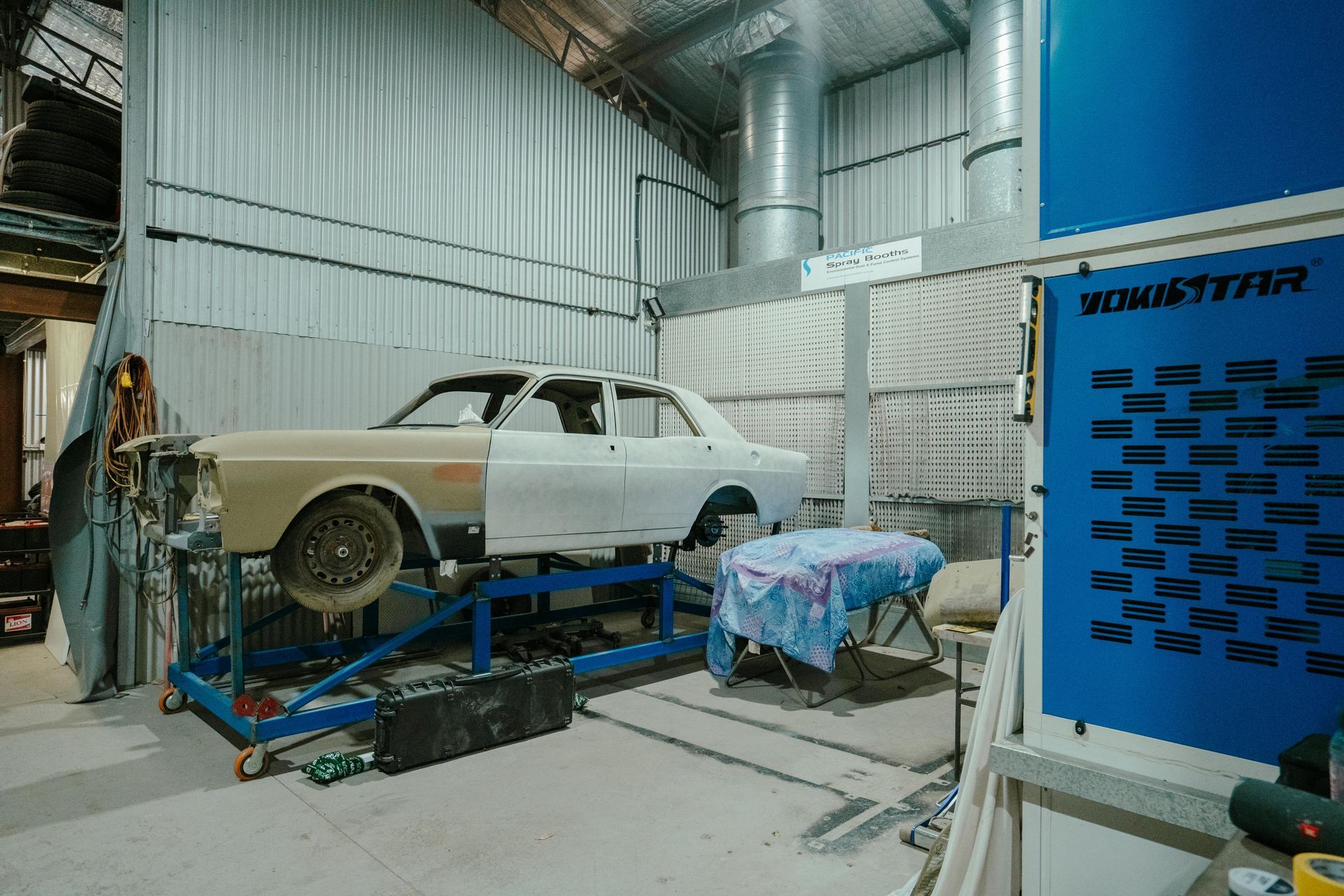 Car being worked on in a paint booth; blue and white color scheme. — 100% Automotive In South Nowra, NSW