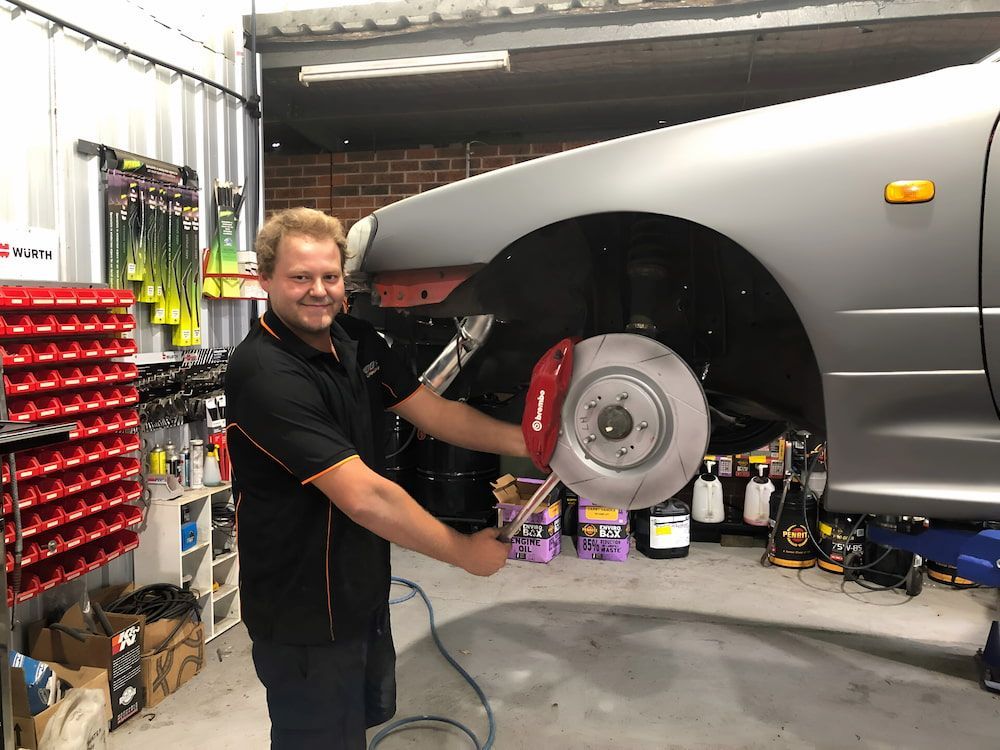 A Man Is Working On A Car In A Garage β 100% Automotive In South Nowra, NSW