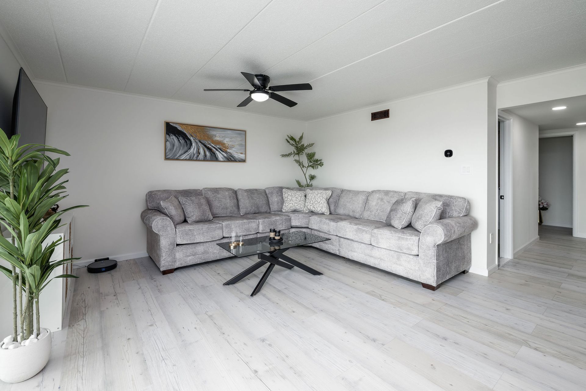 A living room with a large sectional couch and a ceiling fan.