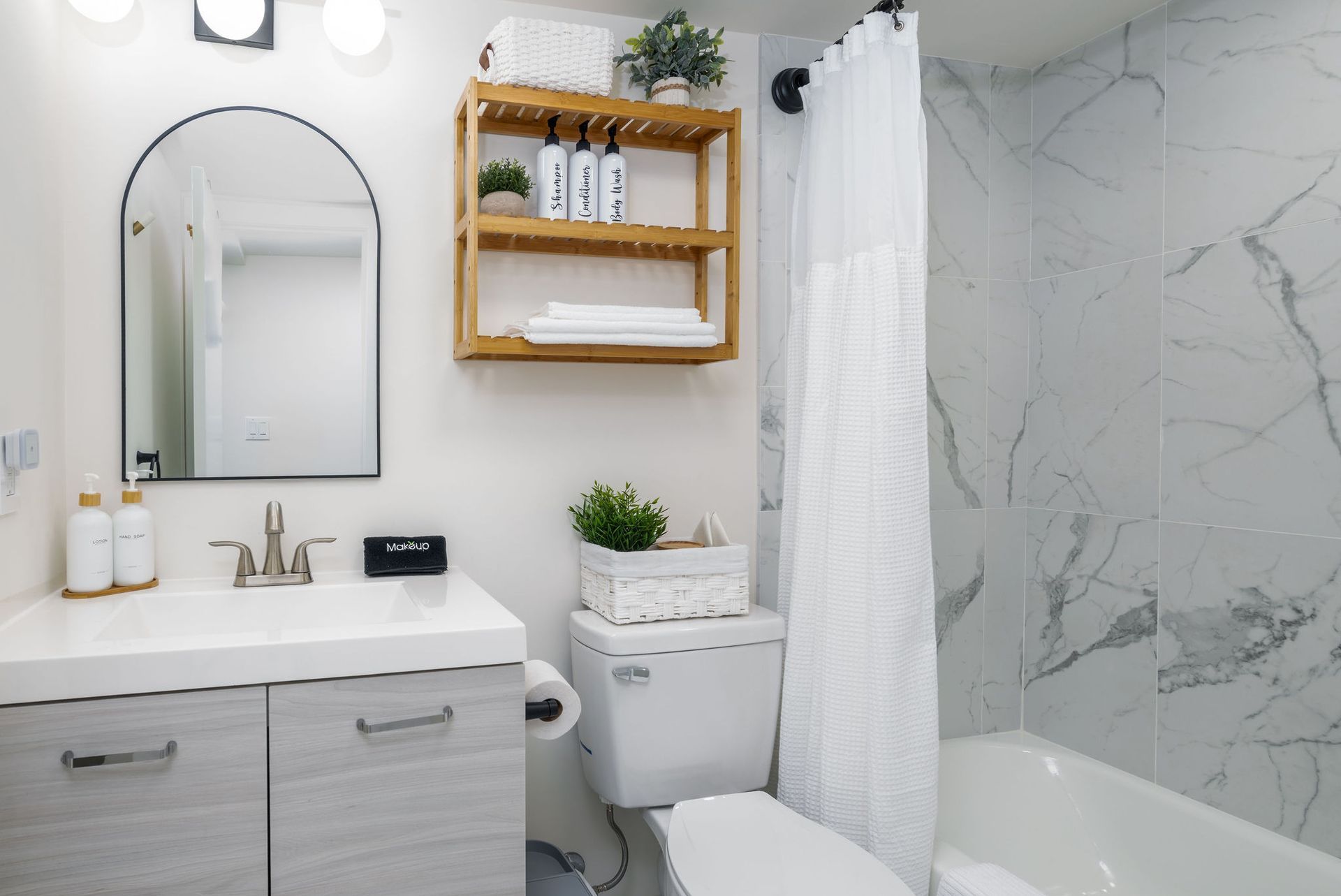 A bathroom with a sink, toilet, shower curtain and mirror.