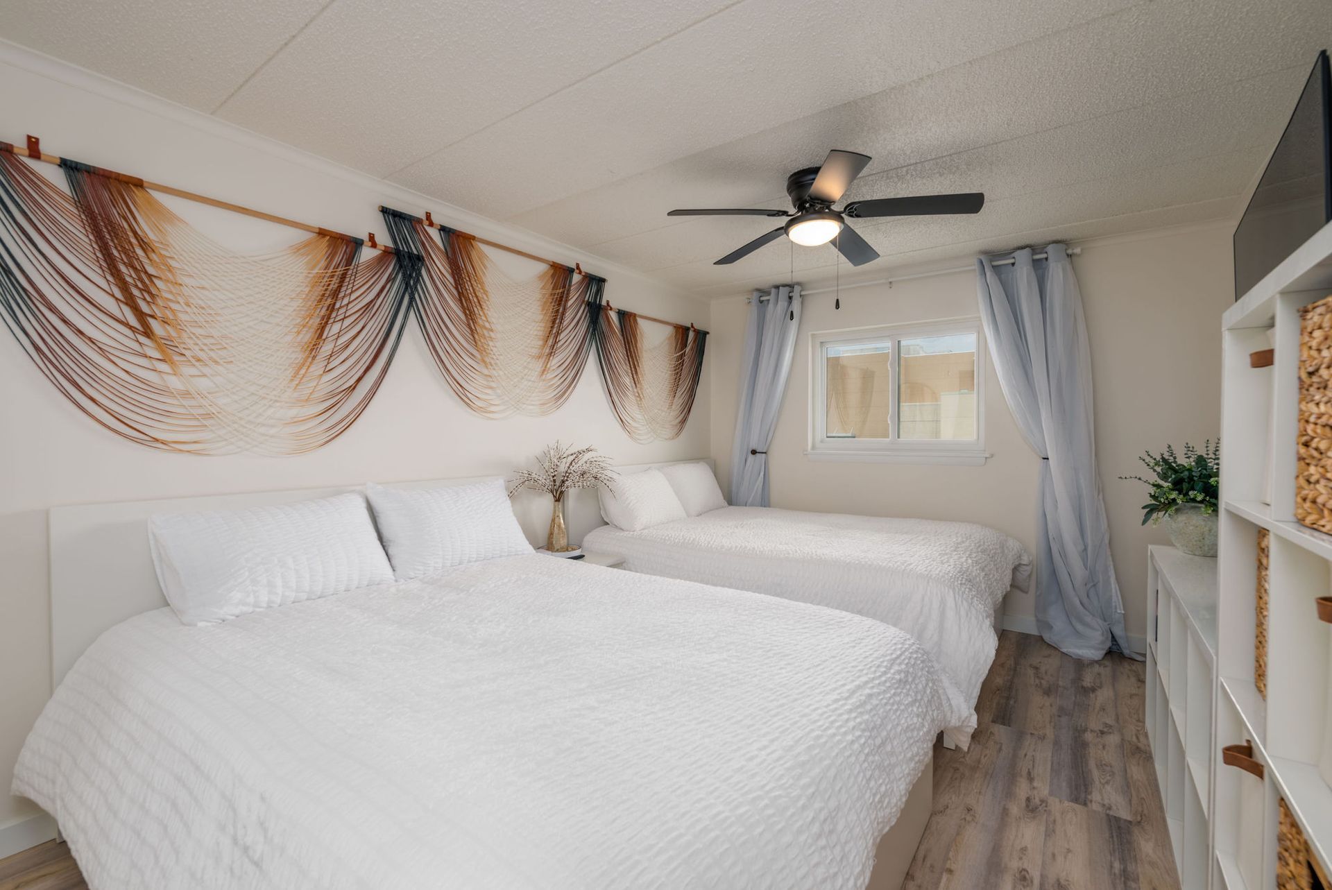 A bedroom with three beds and a ceiling fan.