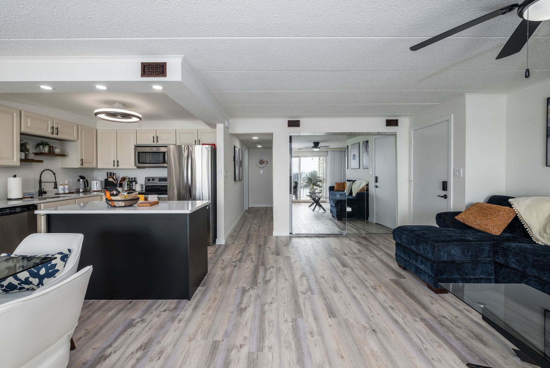 A living room with a couch, chairs, and a ceiling fan.