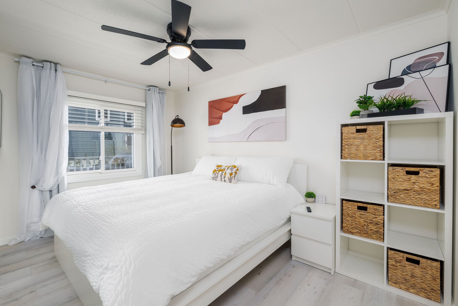 A bedroom with a bed, nightstand, shelves and a ceiling fan.