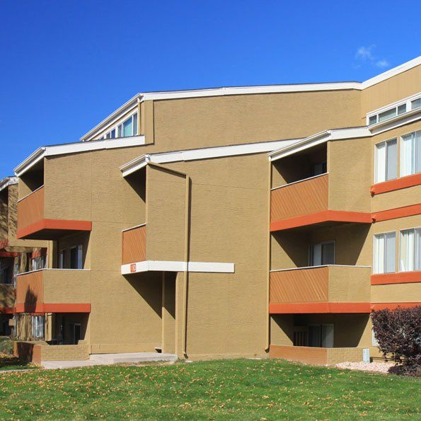 Dark beige apartment building with blue sky behind it