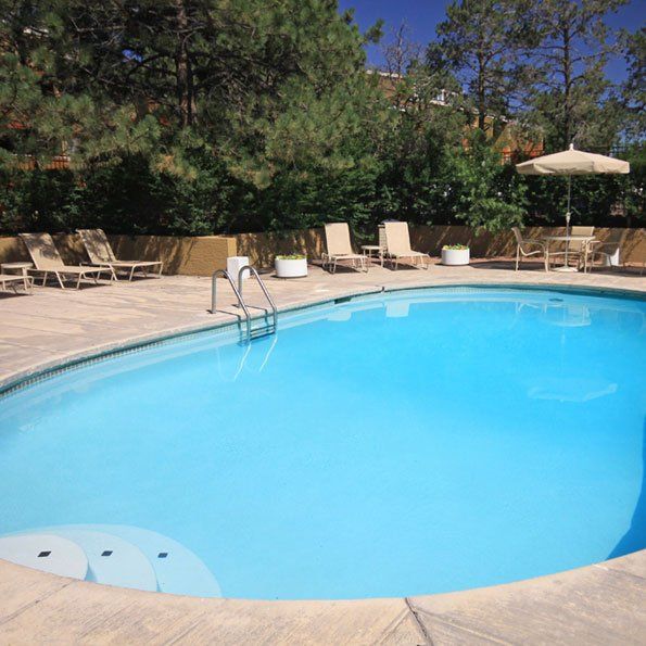 Oval shaped pool with lounge chairs around it