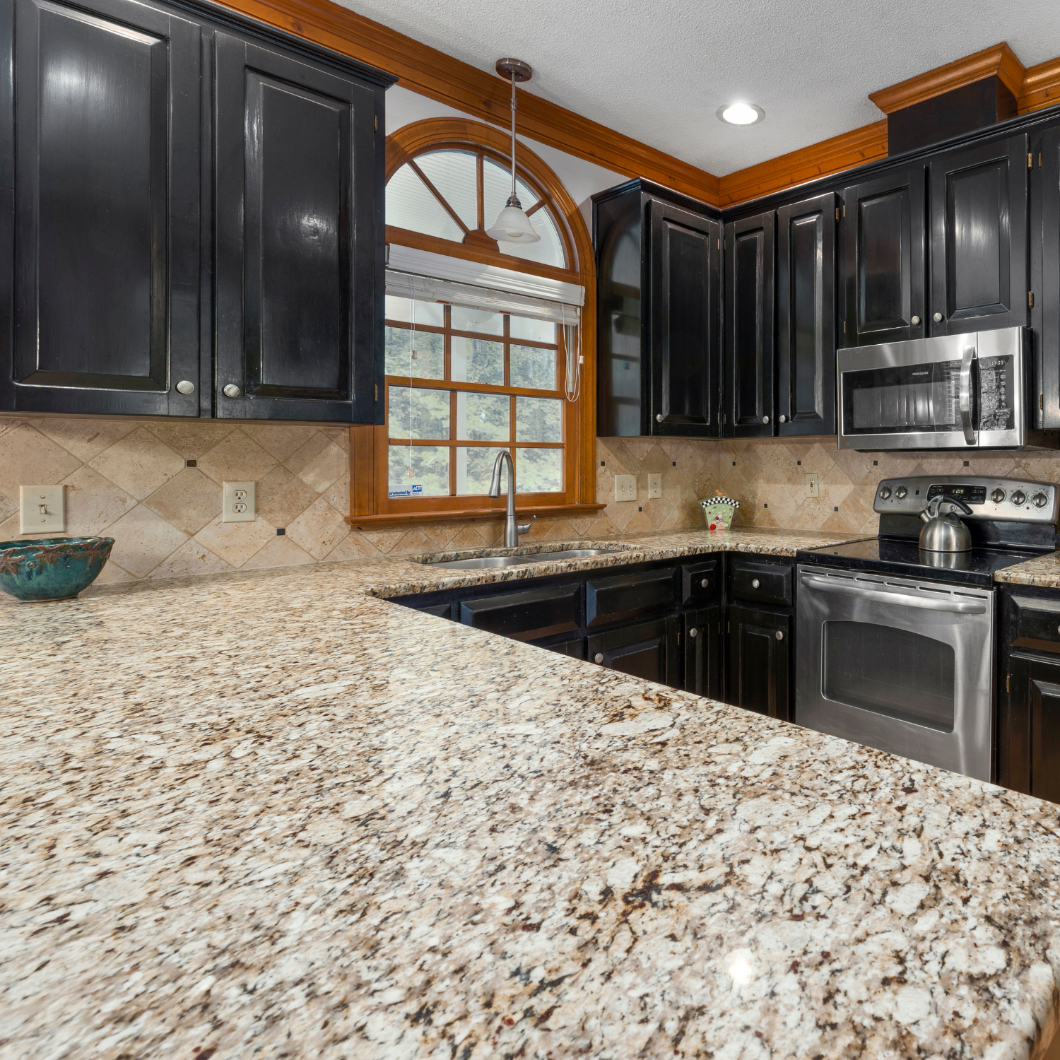 A kitchen with granite counter tops and black cabinets