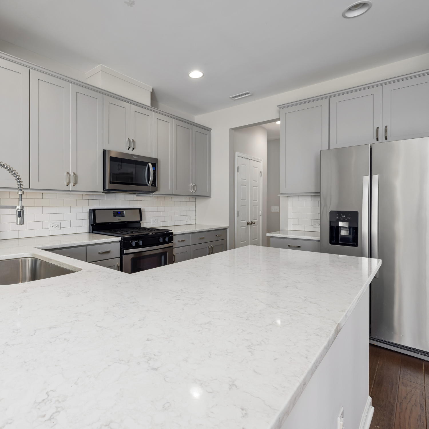A kitchen with stainless steel appliances and white counter tops