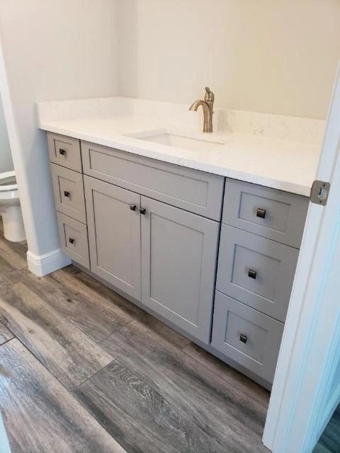A bathroom with a sink , cabinets , drawers and a toilet.