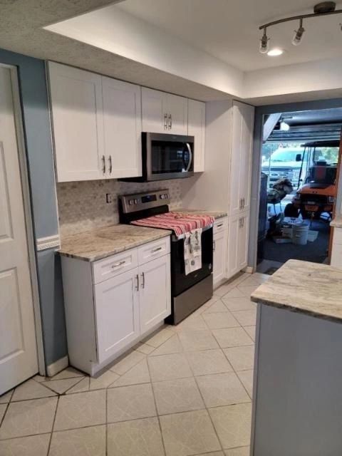 A kitchen with white cabinets a stove and a microwave