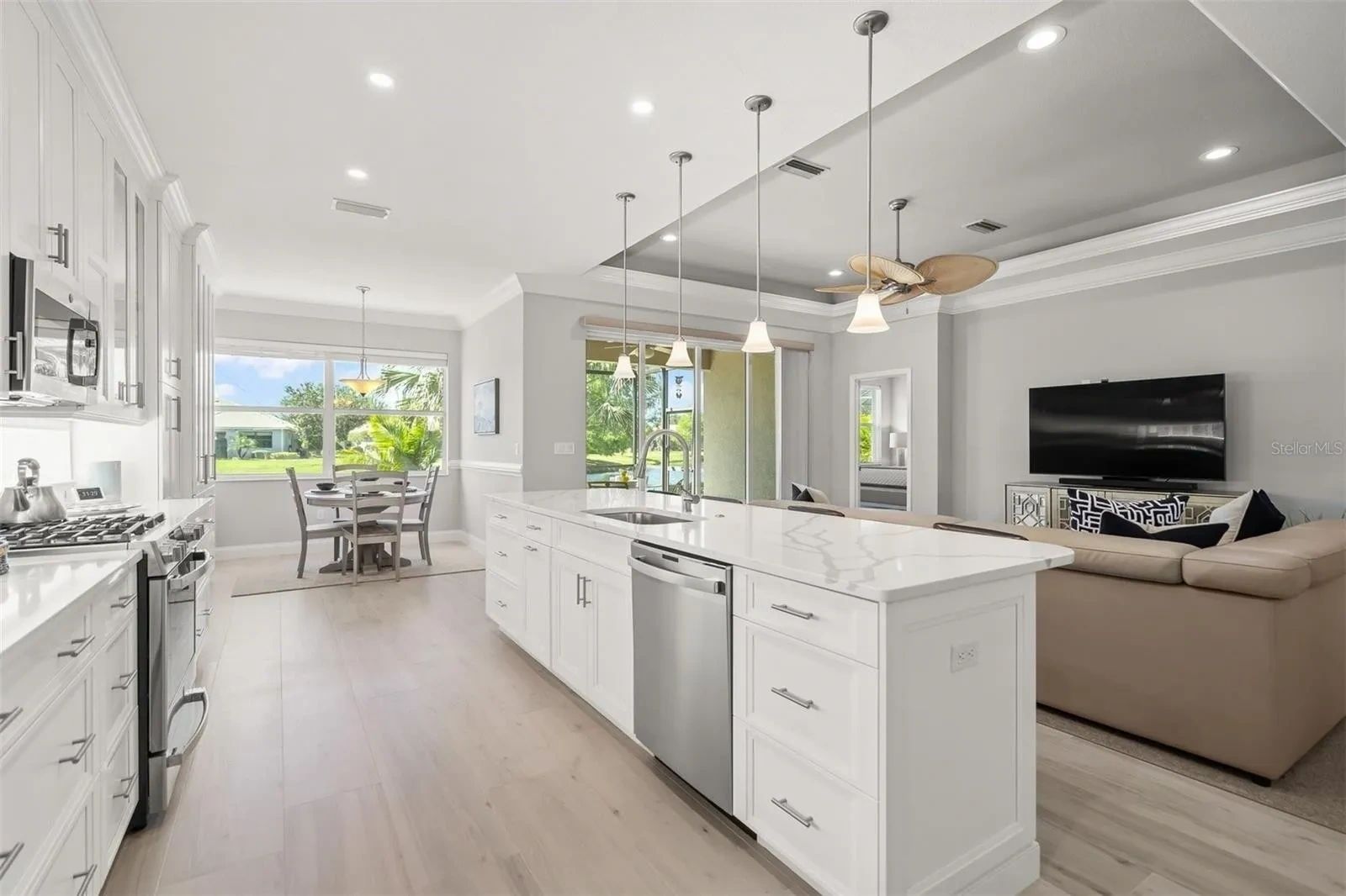 A kitchen with white cabinets and stainless steel appliances and a large island.