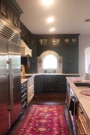 A kitchen with stainless steel appliances and a pink rug.