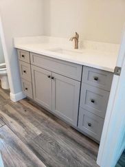 A bathroom vanity with a sink , drawers , and a toilet.
