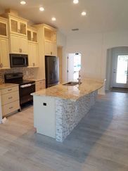 A kitchen with white cabinets , granite counter tops , and a large island.