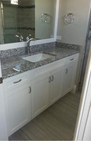 A bathroom with a sink , mirror and granite counter tops.