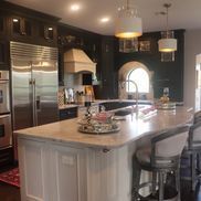 A kitchen with stainless steel appliances , a large island , a sink , and a refrigerator.