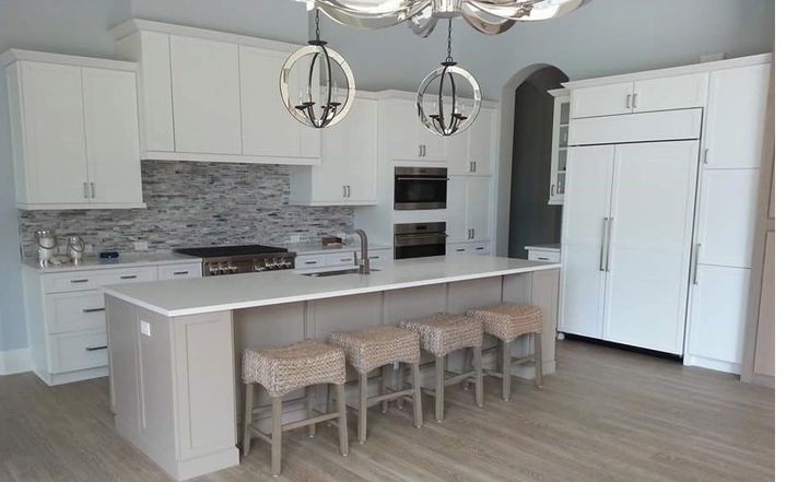 A kitchen with white cabinets and stools and a large island.