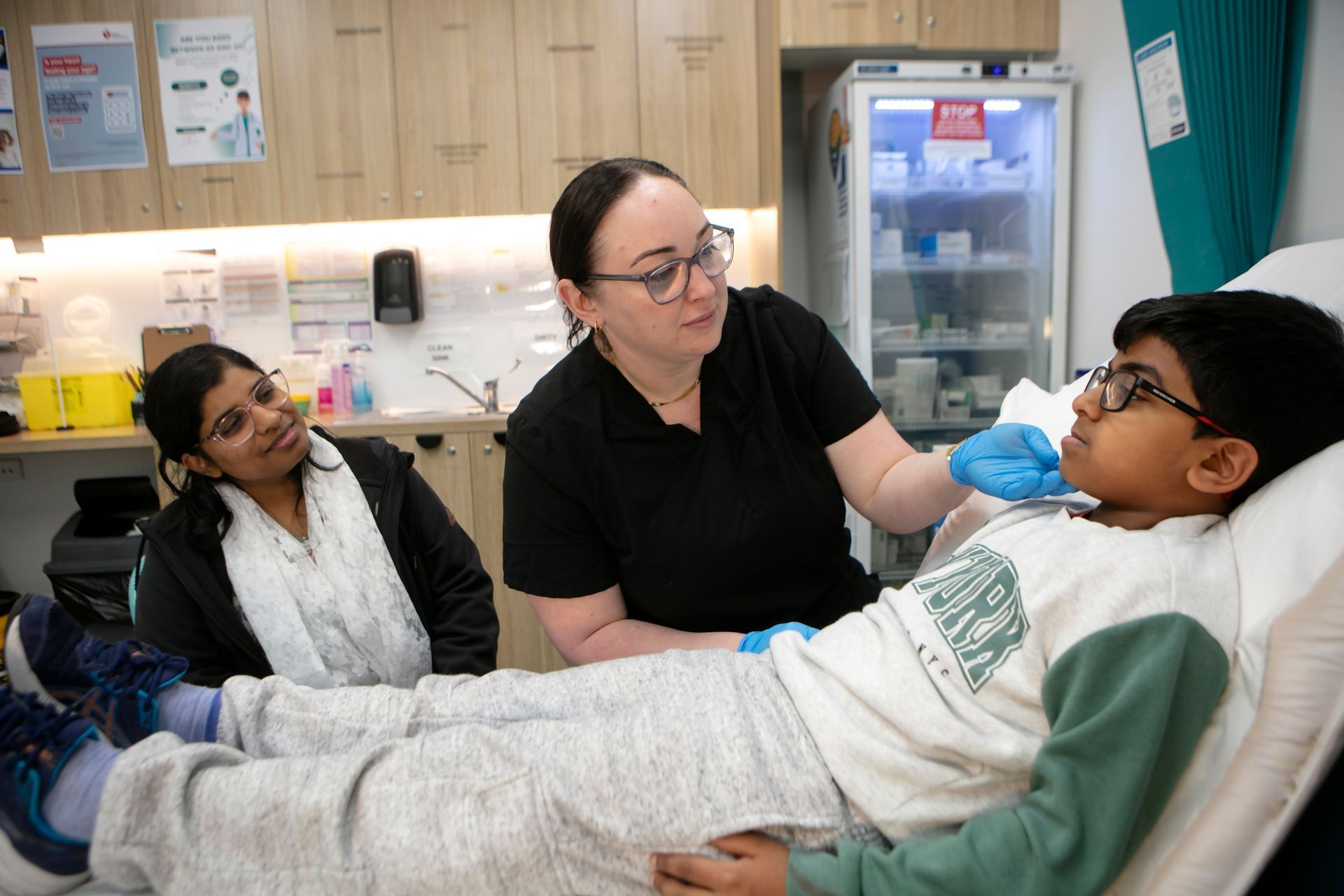 Young patient with mother being tended to by medical professional at UCC.
