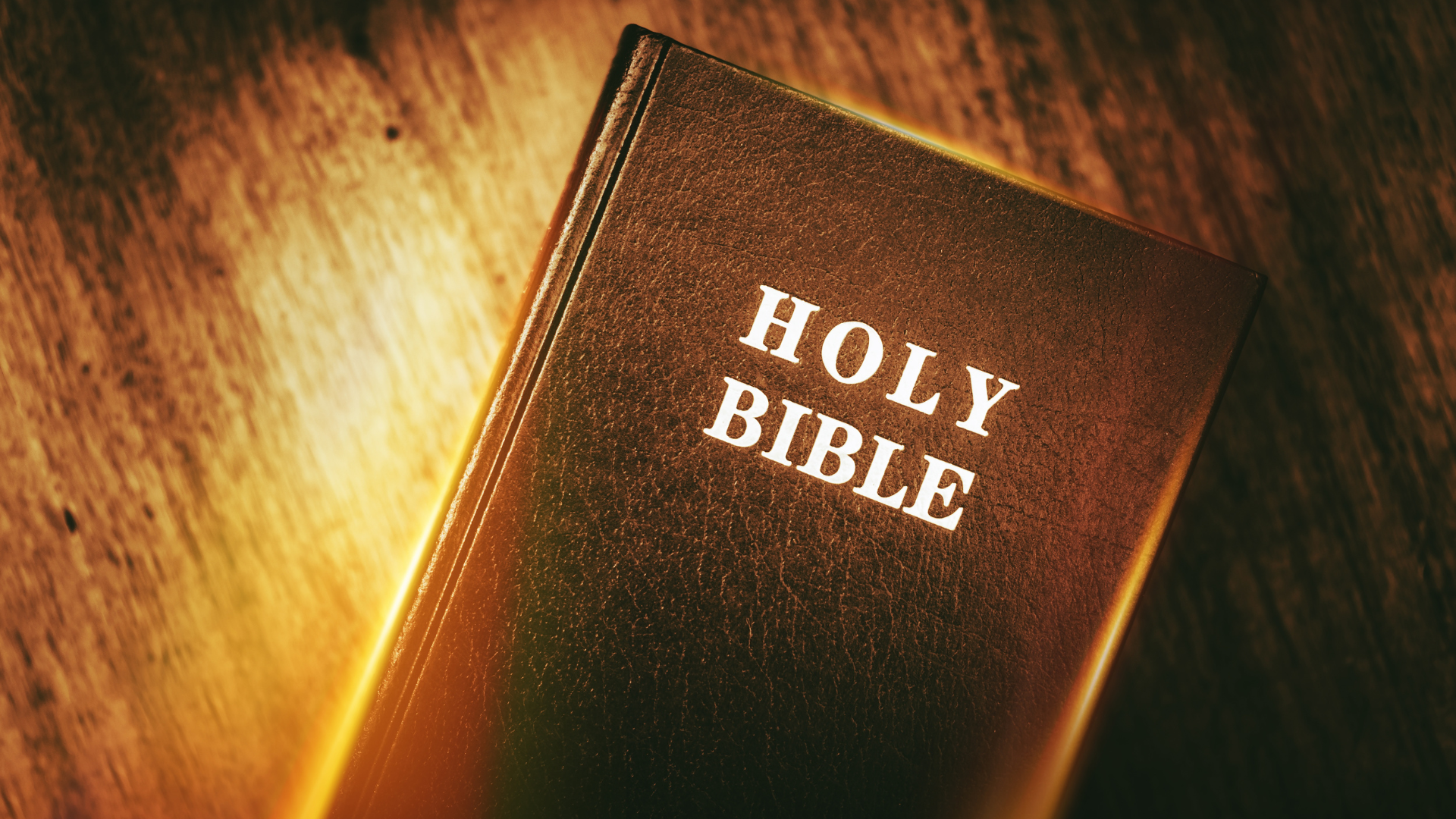 A holy bible is sitting on a wooden table.