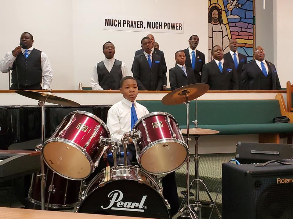 A boy is playing drums in front of a pearl drum set