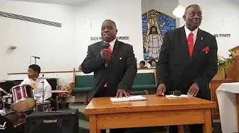Two men in suits and ties are standing at a table in a church.