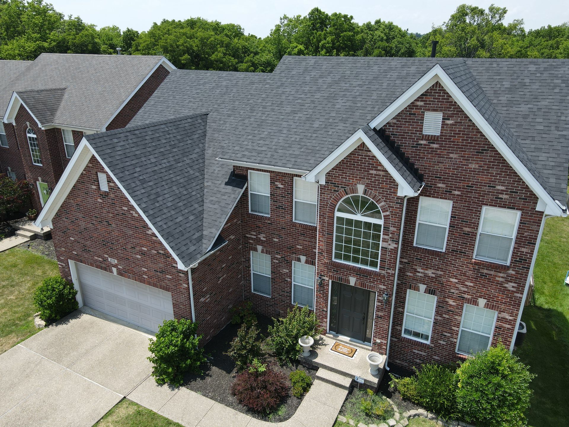 Brick house with dark gray roof, two stories, front door, windows, and attached garage.
